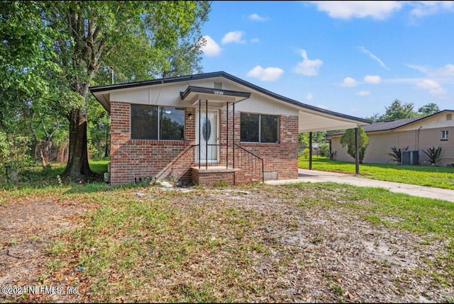 view of front of home featuring a carport, a front lawn, and central AC