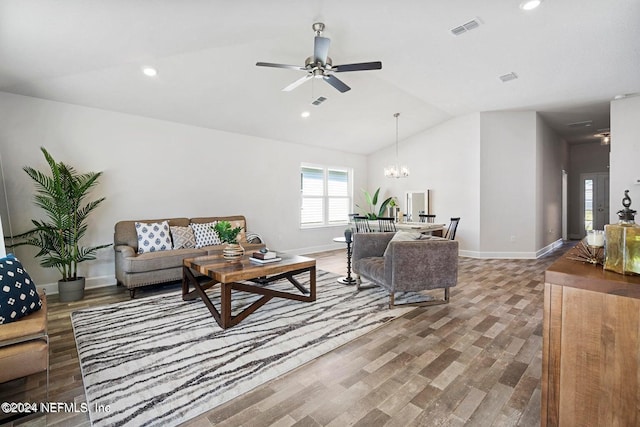 living room featuring ceiling fan with notable chandelier, vaulted ceiling, and dark wood-type flooring