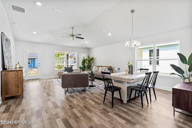 dining area featuring vaulted ceiling, ceiling fan with notable chandelier, and hardwood / wood-style flooring