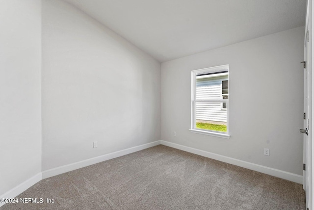 carpeted empty room with lofted ceiling