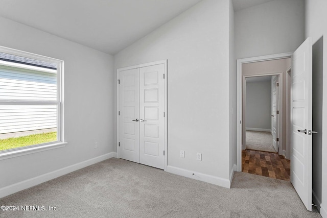 unfurnished bedroom featuring light carpet, a closet, and lofted ceiling