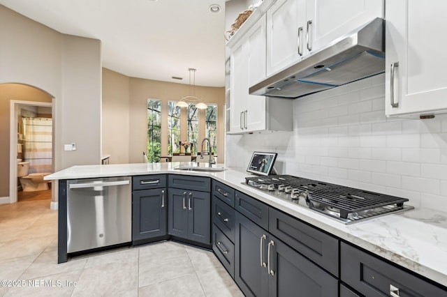 kitchen featuring kitchen peninsula, appliances with stainless steel finishes, tasteful backsplash, sink, and white cabinetry