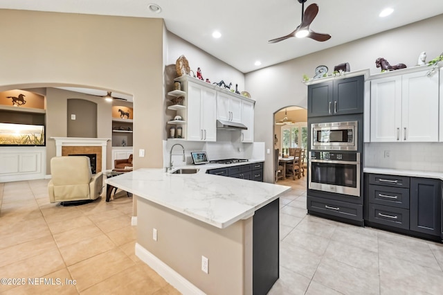 kitchen with sink, light tile patterned floors, white cabinetry, kitchen peninsula, and stainless steel appliances