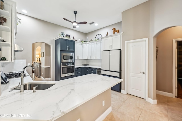 kitchen featuring sink, tasteful backsplash, light stone counters, light tile patterned flooring, and appliances with stainless steel finishes