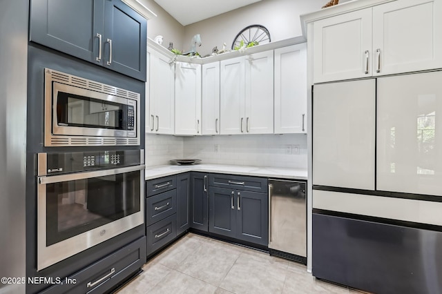 kitchen with built in appliances, white cabinetry, light tile patterned floors, and decorative backsplash