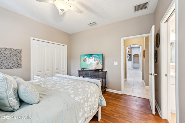 bedroom with a textured ceiling, a closet, ceiling fan, and hardwood / wood-style flooring