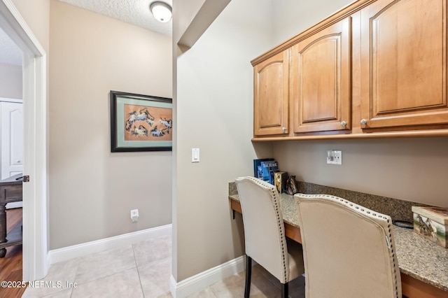 tiled home office with built in desk and a textured ceiling