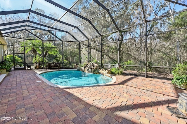 view of pool with glass enclosure, a patio area, and pool water feature