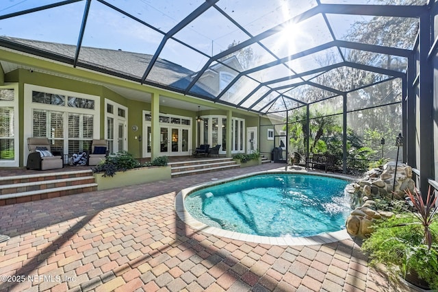 view of pool featuring ceiling fan, french doors, a lanai, pool water feature, and a patio area