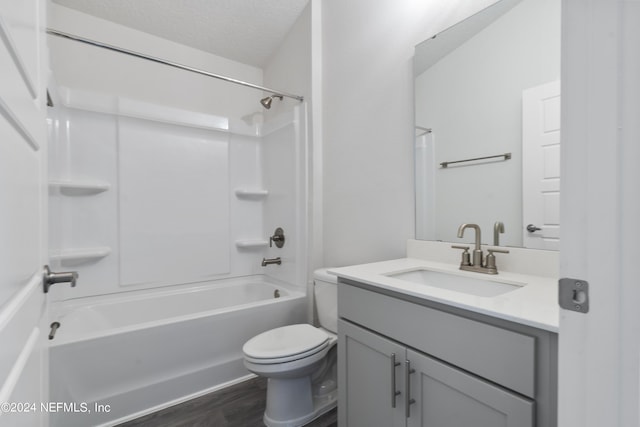 full bathroom featuring tub / shower combination, vanity, a textured ceiling, hardwood / wood-style flooring, and toilet