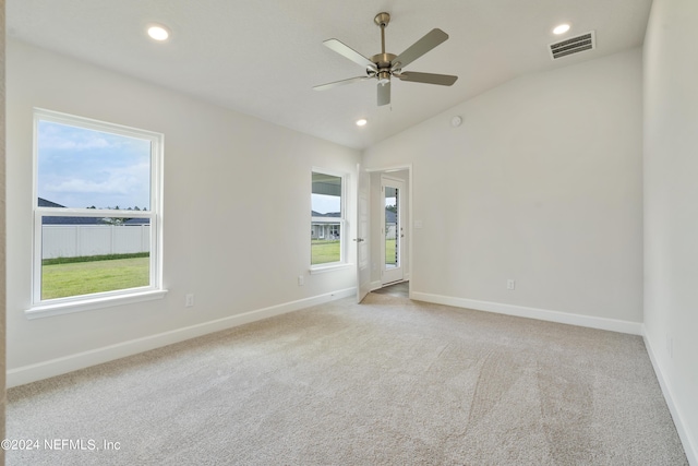 spare room with ceiling fan, light colored carpet, and vaulted ceiling