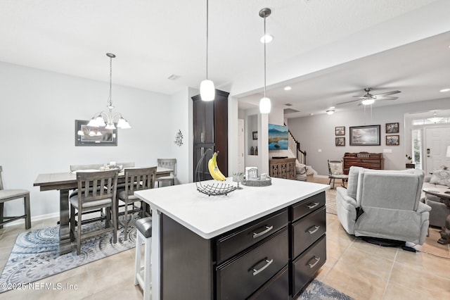 kitchen with decorative light fixtures, a center island, light tile patterned floors, and ceiling fan with notable chandelier