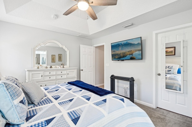 carpeted bedroom with a tray ceiling, ceiling fan, and a textured ceiling