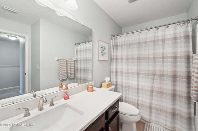 bathroom with vanity, toilet, and a textured ceiling