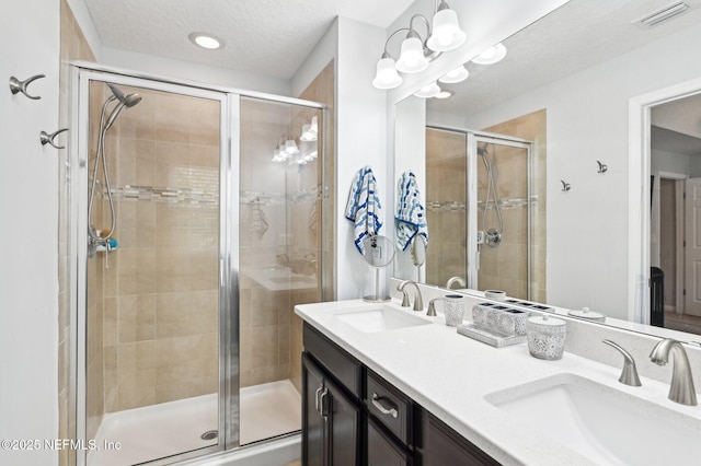 bathroom featuring vanity, a shower with door, and a textured ceiling