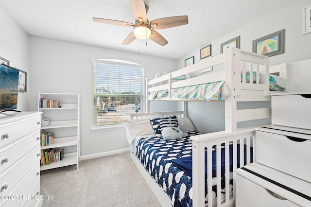 bedroom with ceiling fan, light colored carpet, and a textured ceiling