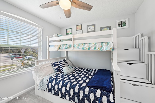 bedroom with multiple windows, ceiling fan, light colored carpet, and a textured ceiling