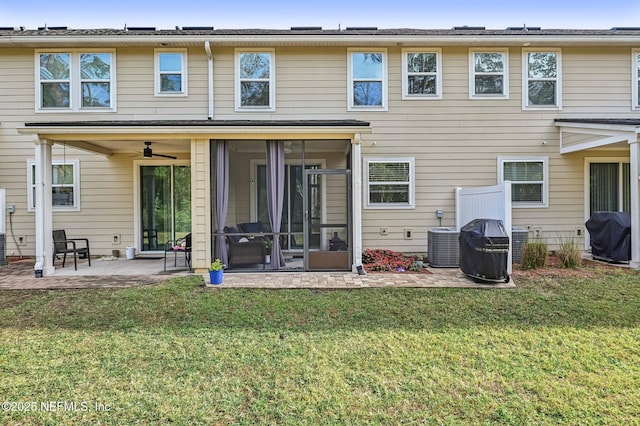 rear view of house with ceiling fan, central AC unit, a patio area, a sunroom, and a lawn