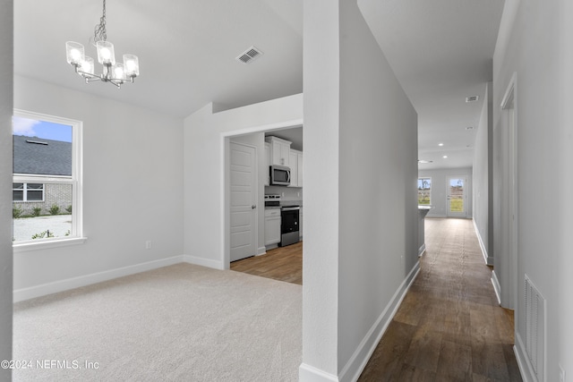 hallway featuring plenty of natural light, light wood-type flooring, and an inviting chandelier