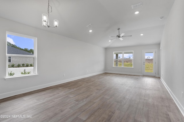 spare room with ceiling fan with notable chandelier, vaulted ceiling, and light wood-type flooring