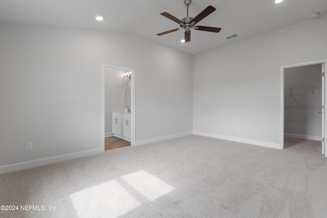 unfurnished bedroom featuring vaulted ceiling, ceiling fan, a spacious closet, light colored carpet, and a closet