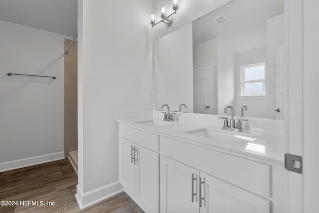 bathroom with hardwood / wood-style flooring, vanity, and a tile shower