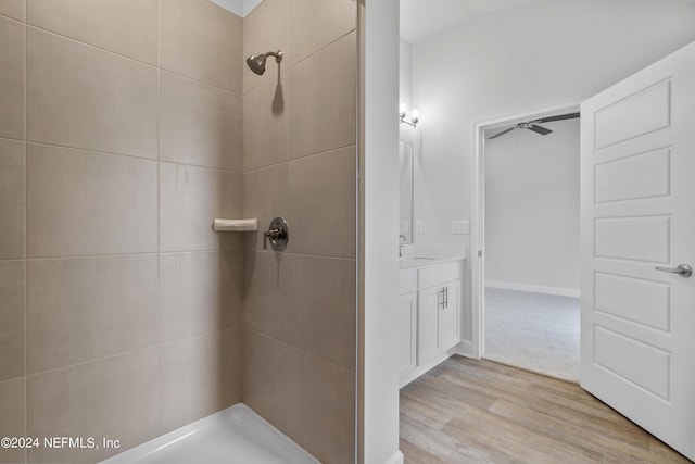 bathroom with ceiling fan, vanity, wood-type flooring, and tiled shower