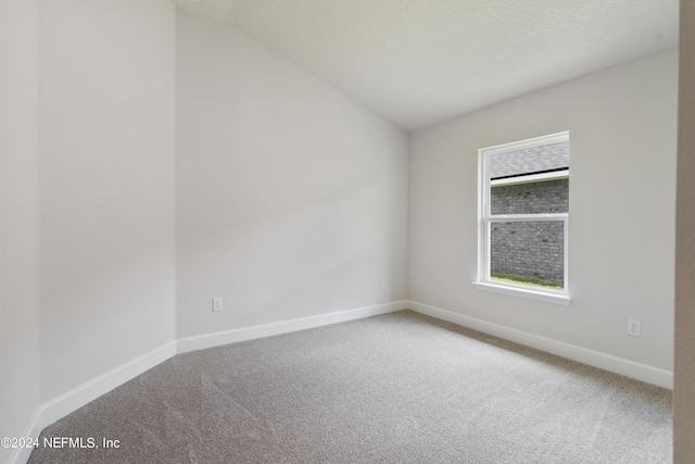 unfurnished room with a textured ceiling, carpet floors, and vaulted ceiling