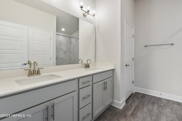 bathroom with tiled shower, hardwood / wood-style floors, and vanity