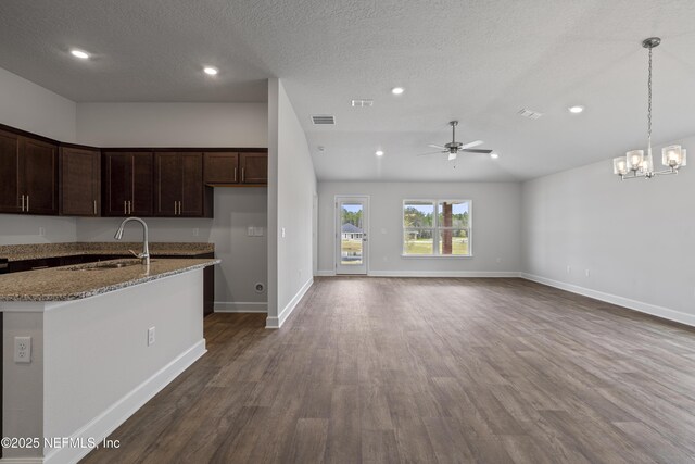 3245 Winding Creek Pl, Green Cove Springs, FL 32043 - kitchen featuring light stone counters, dark brown cabinetry, ceiling fan with notable chandelier, visible vents, and dark wood-style flooring