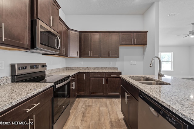 3245 Winding Creek Pl, Green Cove Springs, FL 32043 - kitchen with dark brown cabinetry, a sink, light stone countertops, light wood-style flooring, and stainless steel appliances