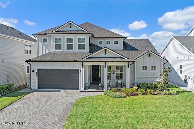 view of front of home featuring a front yard, a porch, and a garage