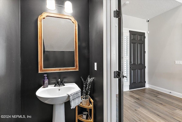 bathroom featuring wood-type flooring and a textured ceiling