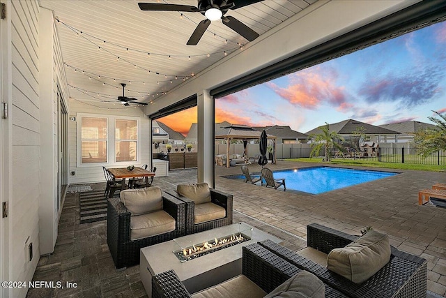 pool at dusk with a fire pit and a patio area