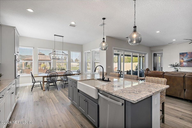 kitchen featuring sink, stainless steel dishwasher, light hardwood / wood-style floors, gray cabinets, and a kitchen island with sink