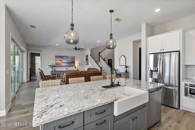 kitchen featuring a center island with sink, white cabinets, hardwood / wood-style floors, and appliances with stainless steel finishes