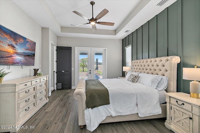 bedroom featuring dark wood-type flooring, access to outside, french doors, a raised ceiling, and ceiling fan