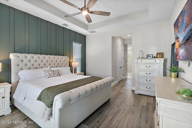 bedroom featuring hardwood / wood-style floors, a textured ceiling, a tray ceiling, and ceiling fan