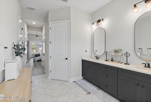 bathroom featuring vanity, ceiling fan, a textured ceiling, and french doors