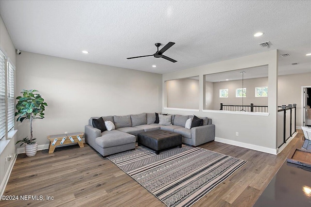 living room featuring ceiling fan, dark hardwood / wood-style flooring, and a textured ceiling