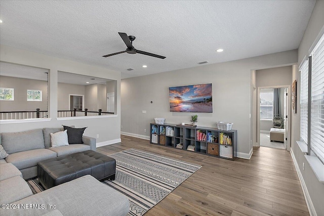 living room featuring ceiling fan, wood-type flooring, and a textured ceiling