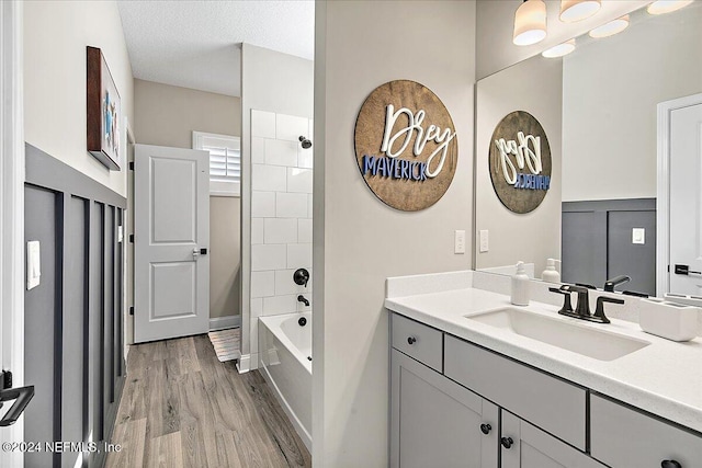 bathroom with bathing tub / shower combination, vanity, a textured ceiling, and hardwood / wood-style flooring