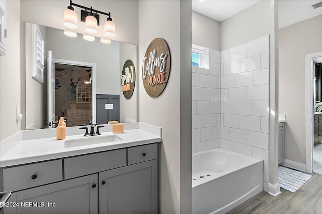 bathroom featuring wood-type flooring, vanity, and tiled shower / bath