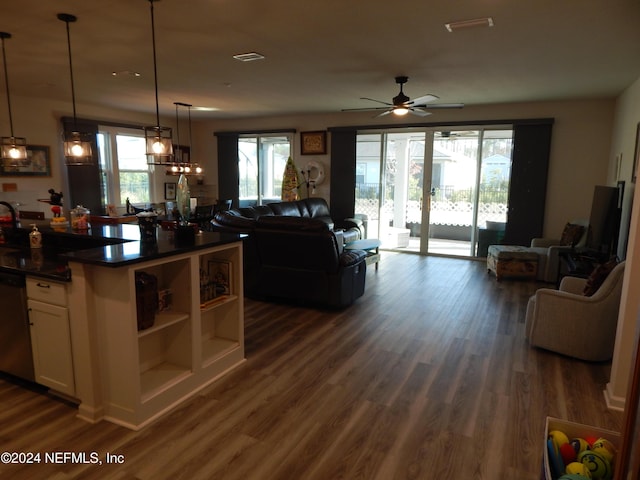 kitchen featuring dark wood-type flooring, white cabinets, hanging light fixtures, stainless steel dishwasher, and ceiling fan