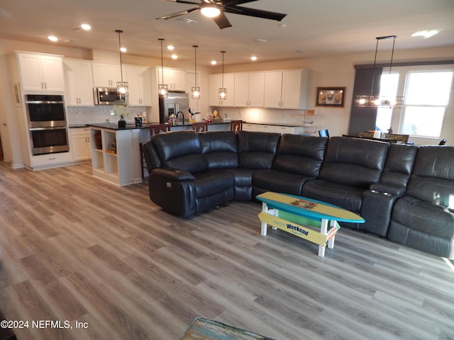 living room with light hardwood / wood-style flooring and ceiling fan