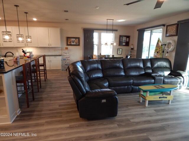 living room featuring dark hardwood / wood-style flooring and ceiling fan with notable chandelier