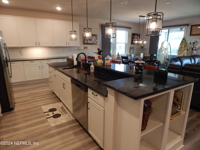 kitchen featuring white cabinetry, stainless steel appliances, light hardwood / wood-style floors, decorative light fixtures, and a center island with sink