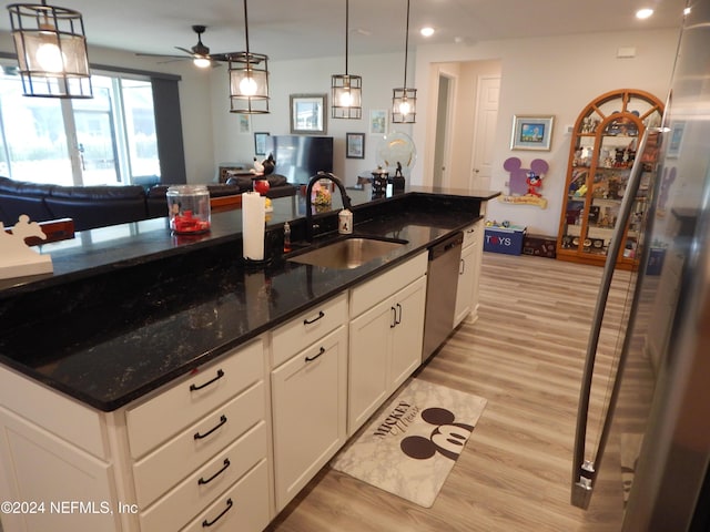 kitchen with dark stone counters, sink, light hardwood / wood-style flooring, stainless steel dishwasher, and white cabinetry