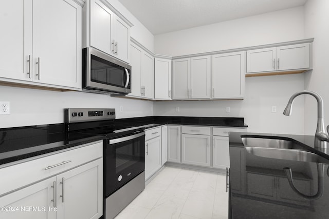 kitchen with white cabinets, appliances with stainless steel finishes, a textured ceiling, and sink