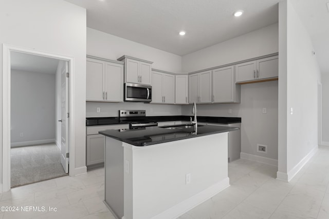 kitchen with appliances with stainless steel finishes, sink, gray cabinetry, and an island with sink